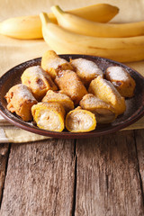 Tasty fried bananas in batter with powdered sugar. vertical
