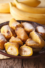 Fried bananas sprinkled with powdered sugar close-up. Vertical
