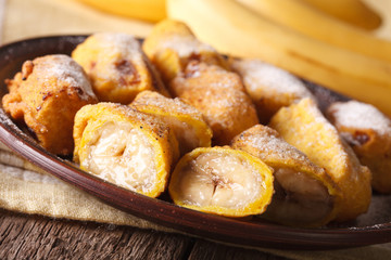 Fried bananas sprinkled with powdered sugar close-up. horizontal

