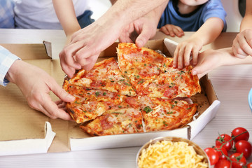 Happy family eating pizza on the wooden table