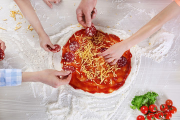 Family hands making a pizza , top view