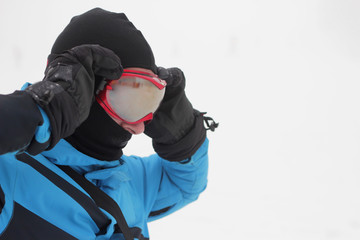 Man in snowboard goggles over snow background