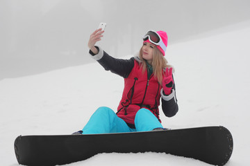 Young girl snowboarder making selfie over white snow background