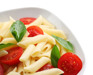 Plate of pasta with cherry tomatoes and basil leaves isolated on white