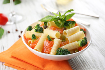 Plate of pasta with salmon and broccoli on table closeup