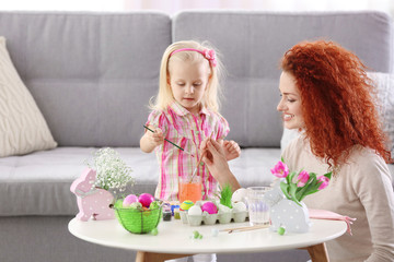 Mother and daughter decorating Easter eggs, indoors