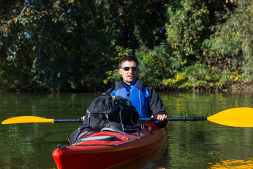 The man is kayaking on the river.