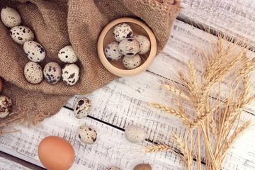 Quail and chicken eggs on rustic wooden background. Top view