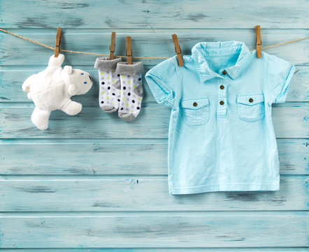 Baby boy t-shirt, socks and white toy bear on a clothesline