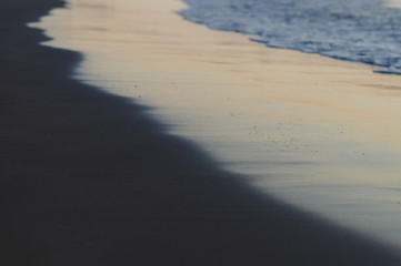 Fototapeta na wymiar Blurred background of waves and black sand beach