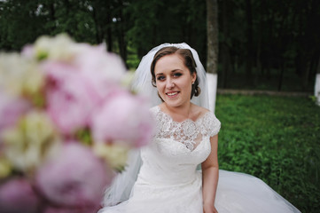 Fototapeta na wymiar Beautiful bride showing peonies wedding bouquet in hand