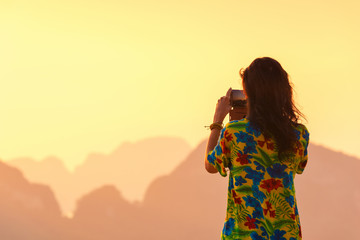 Rear view of woman taking photos of landscape view Phang nga island, Thailand. Travel concept.