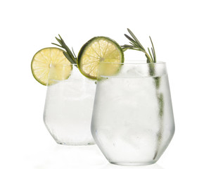 Gin and tonic cocktail with lime over white background.