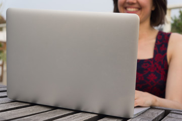 Smiling young woman and laptop outdoors