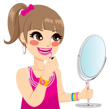 Cute little girl playing grown up with pink lipstick makeup while looking on mirror