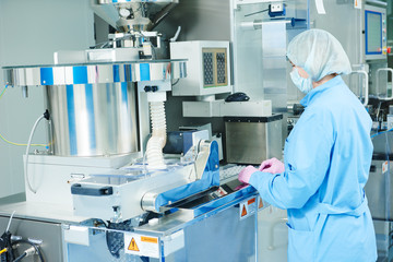 Pharmaceutics. Pharmaceutical worker operates blister packaging machine  - obrazy, fototapety, plakaty