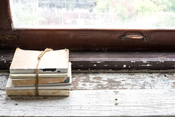 The stack of book on old plank at the windowsill
