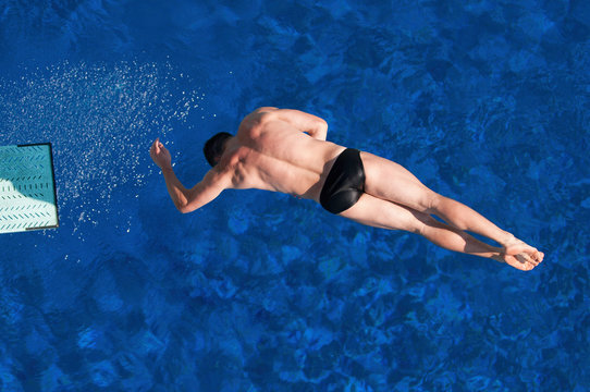 Sport diving from springboard. Male diver spinning in a difficult dive - Powered by Adobe