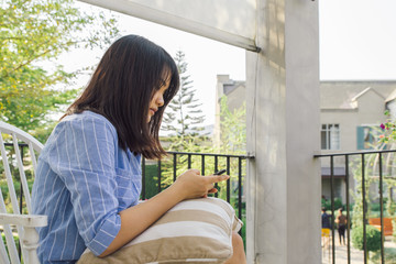 Woman typing text message on smart phone in a cafe. Cropped image of young woman sitting at a table with a coffee using mobile phone.