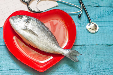 Fish on red heart plate and stethoscope cardiology diet concept
