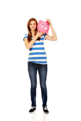 Happy teenage woman holding piggybank