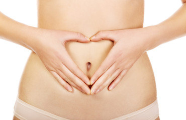 Woman is having heart shape made from hands on her belly