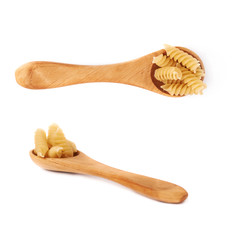 Set of wooden spoon filled with dry rotini pasta over isolated white background