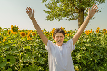 Caucasian boy raising arms on sunflower fields