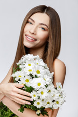 Obraz na płótnie Canvas Beautiful Woman with Clean Fresh Skin holding flowers