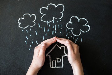 hands protects a house from the elements - rain or storm
