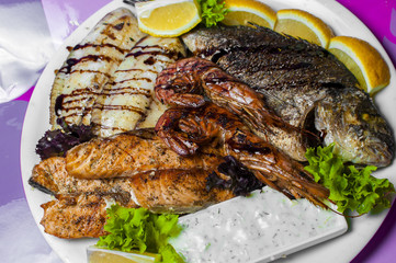 Тарелка с морепродуктами: Несколько видов рыбы в кляре, раки, приправленные зеленью , лимоном и соусом.