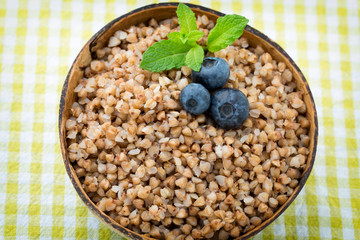 Buckwheat porridge in a bowl with mint leaves and blueberries.