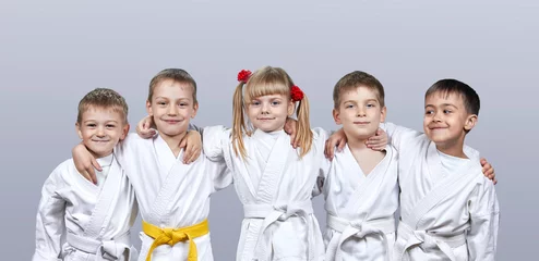 Foto auf Acrylglas Kampfkunst Auf grauem Hintergrund kleine Sportler im Karategi