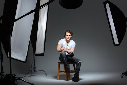 Male photograph sitting on the chair in professinal studio