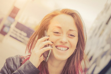 Young attractive caucasian girl laughs while is calling with her smartphone