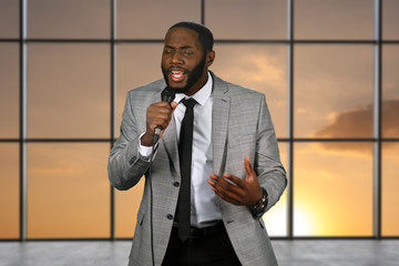 Black singer holding microphone. Singing man on sunset background. Top blues vocalist on stage....