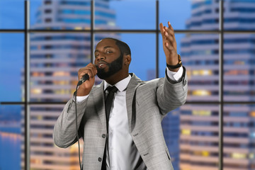Black preacher speaking into microphone. Bearded preacher on evening background. Evening prayer in...