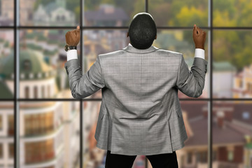 Joyful afro businessman wearing jacket. Back view of elated manager. Huge victory for the company....