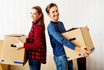 Fototapeta na wymiar Happy couple carrying cardboard boxes in new home