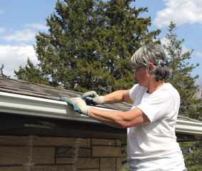 Woman spring cleaning rain gutters
