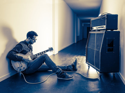 Playing his electric guitar in the hallway