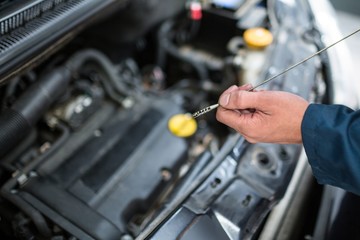 Mechanic checking the oil level in a car engine