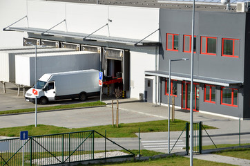 Modern logistics center, white van and trailers standingon ramp
