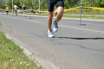 Fototapeta premium Motion blurred legs of runner in the street race (marathon) in sports gear.
