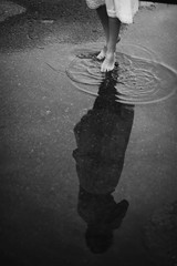 Woman walking barefoot through puddle outdoors
