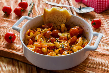 Shrimps in white baking dish on wooden background. Baked with cherry tomatoes and feta cheese.