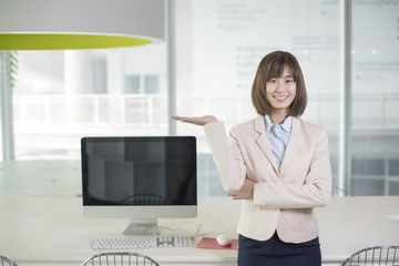 Fototapeta premium Attractive asian business woman showing something on workplace