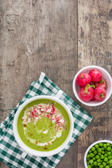 Pea cream with radishes on a rustic wooden background
