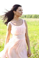Fototapeta na wymiar Beautiful woman standing in a field pink dress, fashion style, the concept of portrait outdoor
