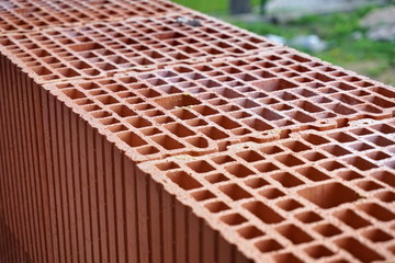 Row of red bricks with the inner holes in the shape of honeycomb on the construction site 